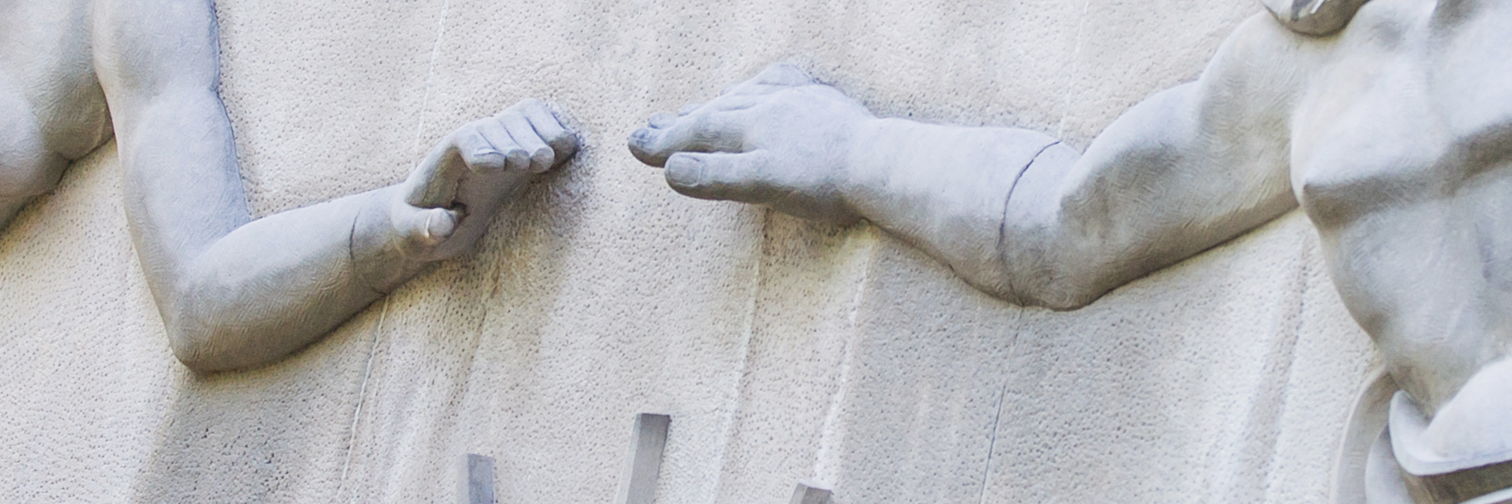 Limestone relief sculpture of two hands reaching for each other.