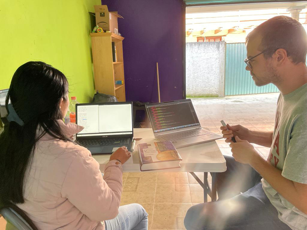 Two people work in front of laptop computers.