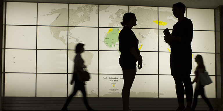 Silhouettes of people in front of a world map. 